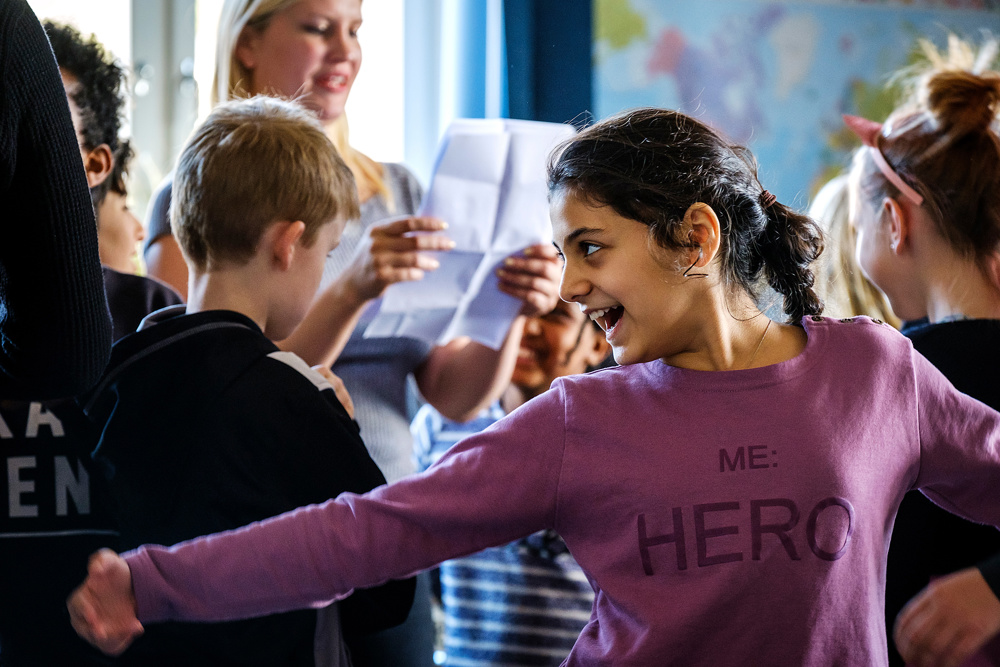Glada barn i ett klassrum som arbetar med teater.