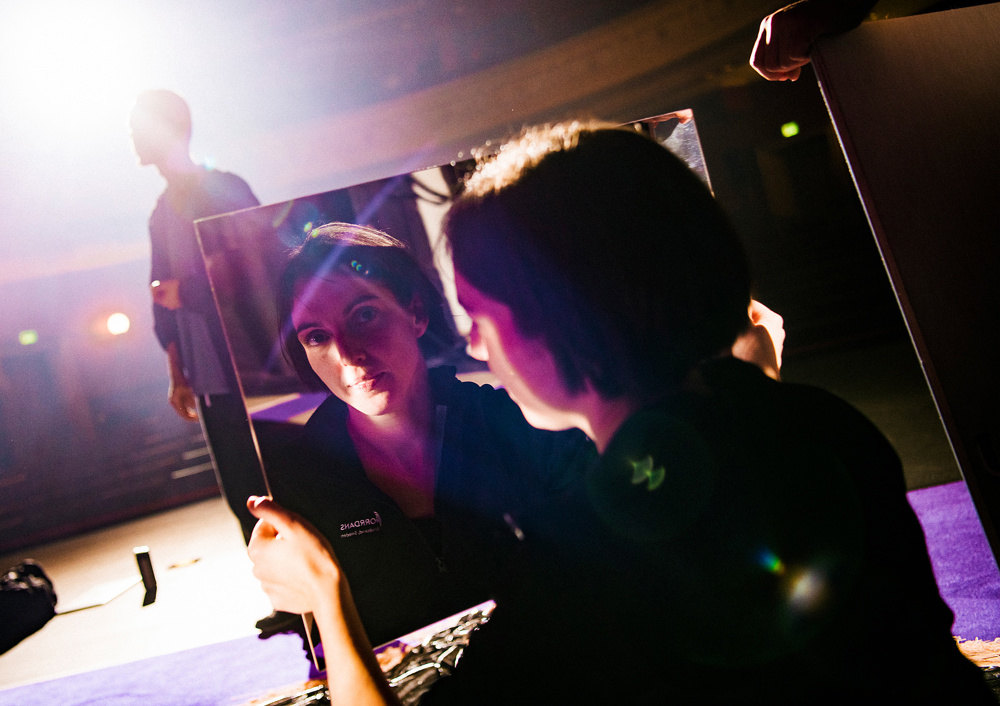 En mörkhårig kvinna möter betraktarens blick i en spegel.