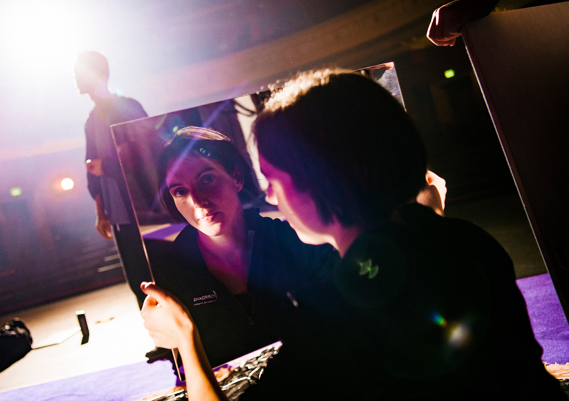 En mörkhårig kvinna möter betraktarens blick i en spegel.