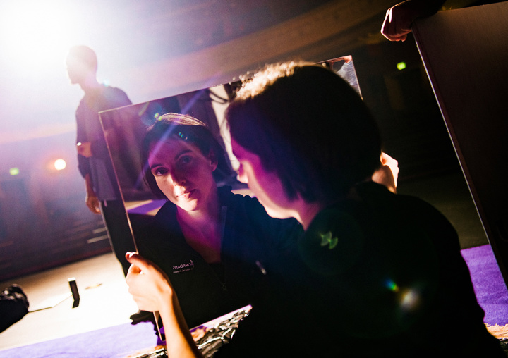 En mörkhårig kvinna möter betraktarens blick i en spegel.