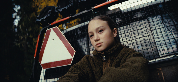 En tonårig flicka på flaket av en AM-traktor