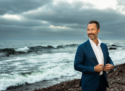 En man i skjorta och kavaj framför ett hav.