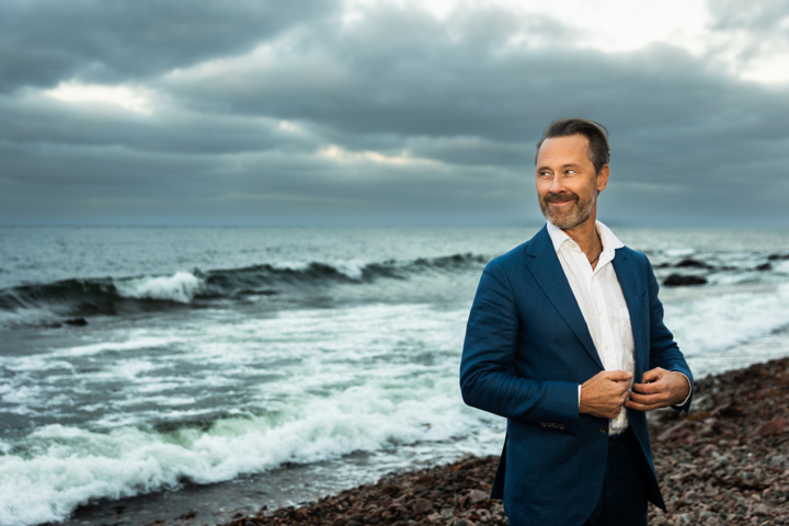 En man i skjorta och kavaj framför ett hav.