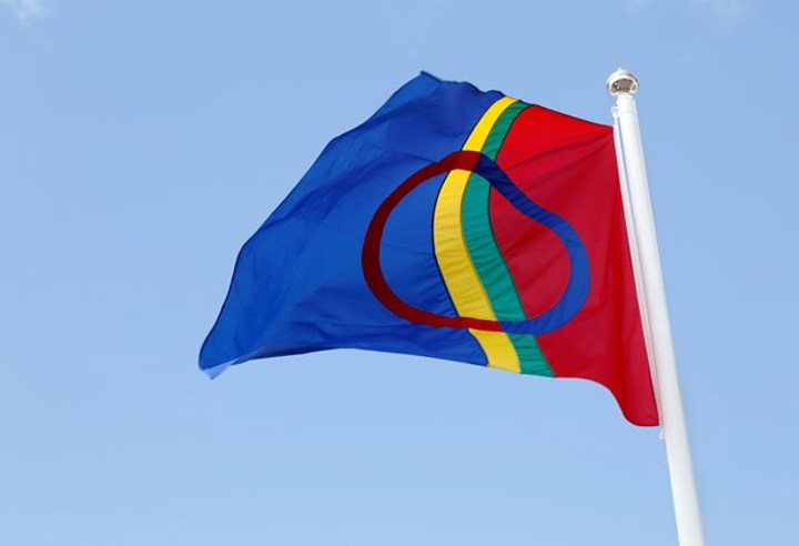 Samernas flagga hissad på en flaggstång med blå himmel i bakgrunden.